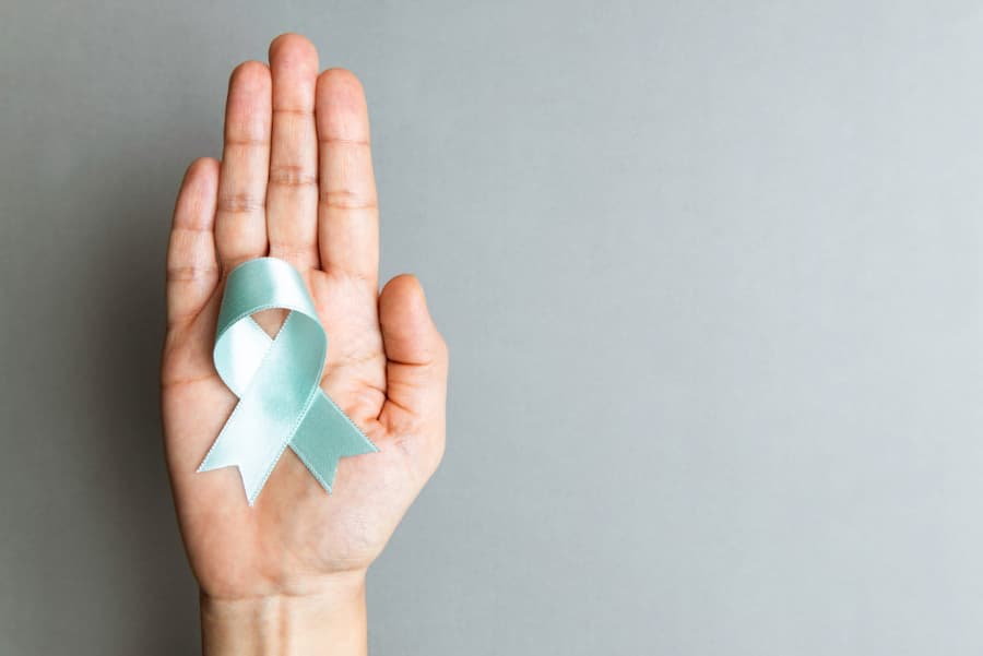 Patient holding blue ribbon in support of prostate cancer awareness