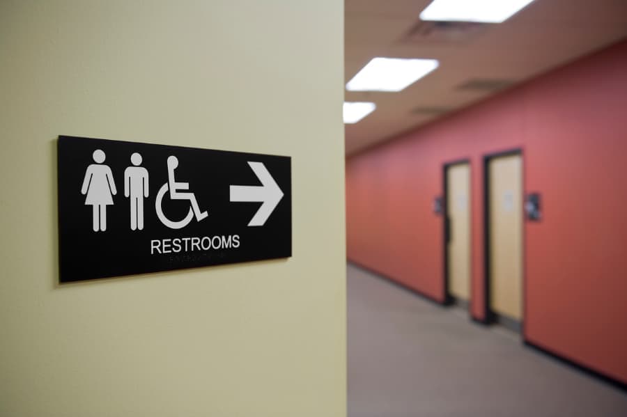 Restroom sign pointing toward bathrooms in office building