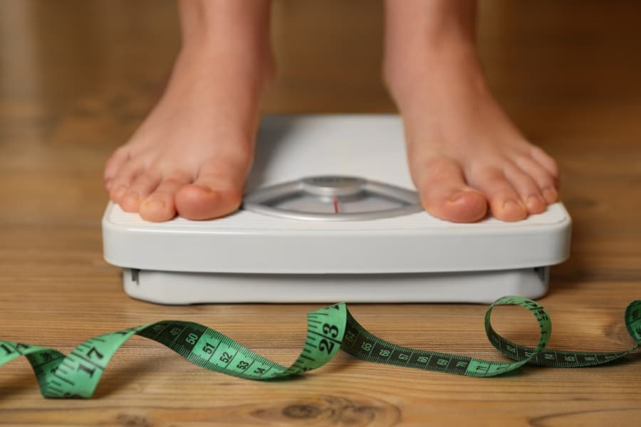 Person standing on top of scale monitoring weight gain