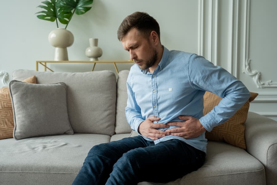 Person experiencing abdominal pain at home on couch