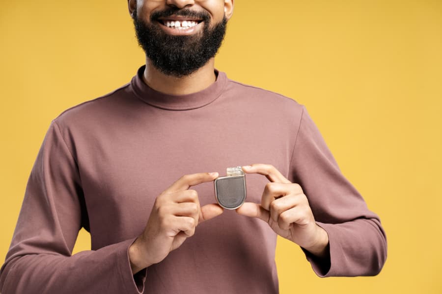 Happy smiling patient holding pacemaker