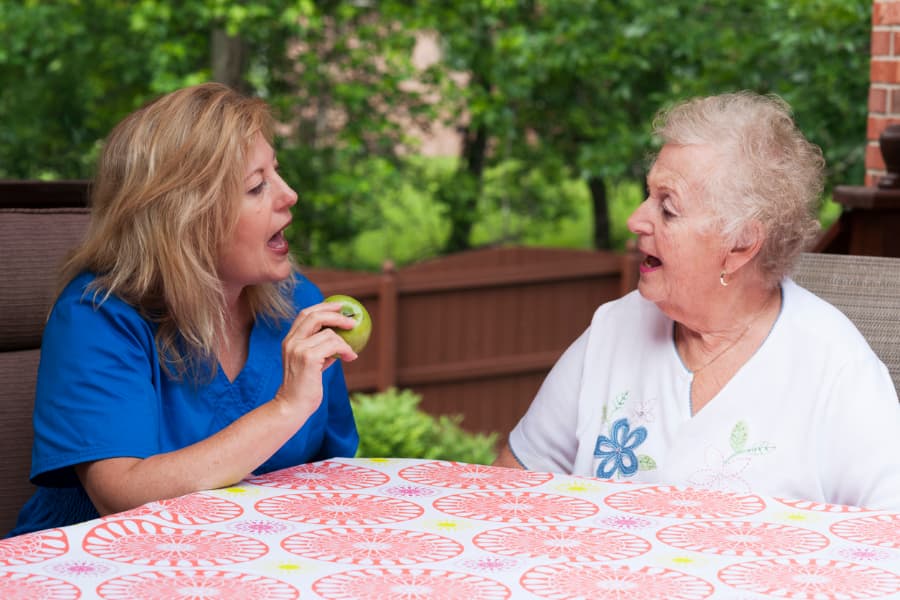 Speech therapist with stroke patient outdoors during home health therapy session