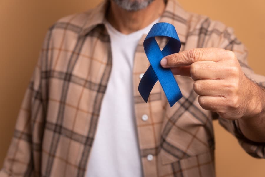 Person holding blue ribbon for prostate cancer awareness
