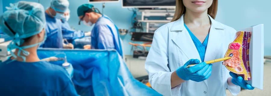 Nurse pointing at breast model with surgeons operating on patient in background