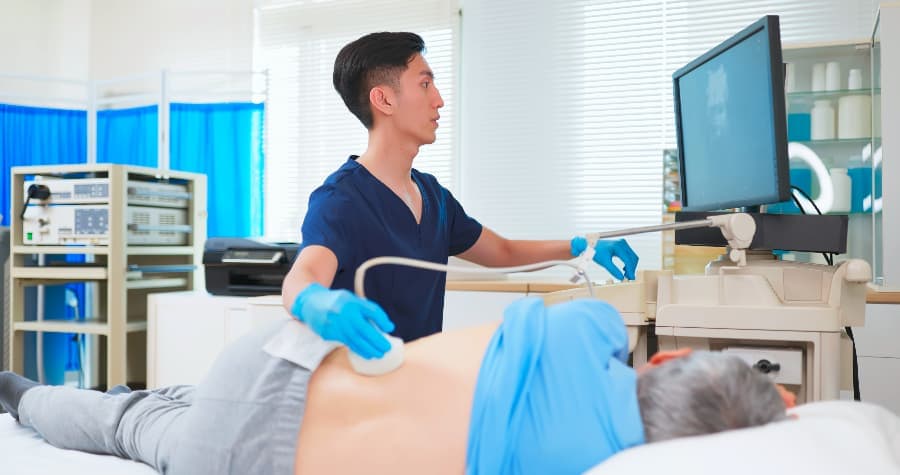 Radiology tech performing kidney ultrasound on elderly patient